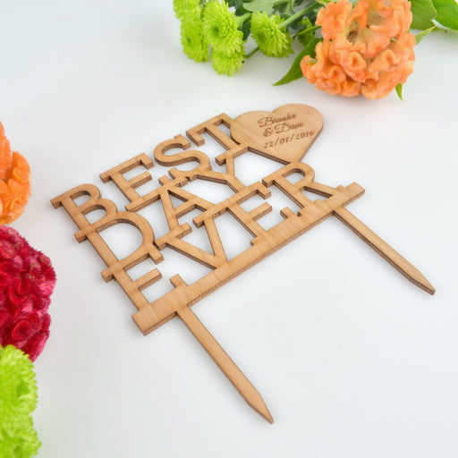 Personalised wooden wedding cake topper with engraved names displayed on rustic wedding cake