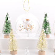 Decorative scene with Christmas trees and a snow globe featuring an angel and 'Charlotte' text.