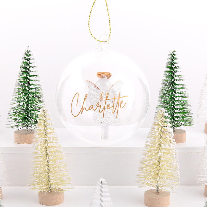 Decorative scene with Christmas trees and a snow globe featuring an angel and 'Charlotte' text.