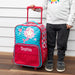 Child standing beside a custom mermaid rolling suitcase with extendable handle.