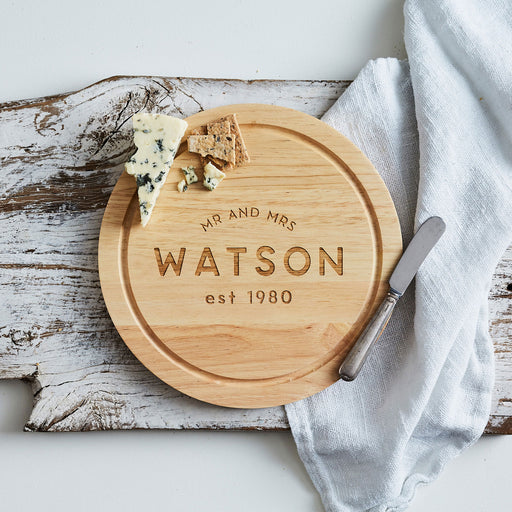 Personalised round wooden cheese board with engraved anniversary design.