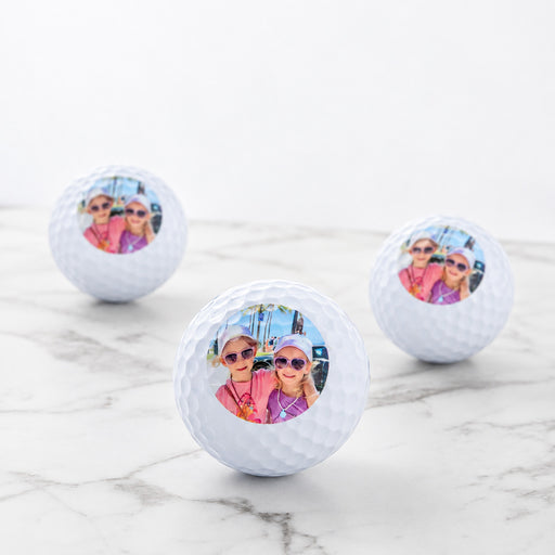 Set of three personalised golf balls with custom photo, presented in a black gift box.