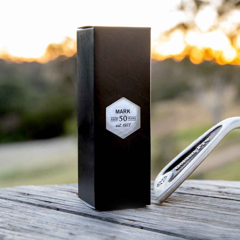 Set of three custom golf balls with initials, presented in a sleek black box – ideal for golf-themed birthday gifting.