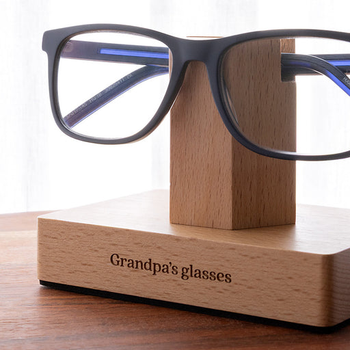Custom wooden glasses holder with engraved base, designed to organise one pair of reading glasses on a bedside table or desk.