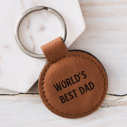 Engraved tan leatherette "World's Best Dad" keyring with black laser engraving and durable silver metal ring, ideal for birthdays and Christmas.